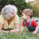 grand mère avec son petit fils dans l'herbe