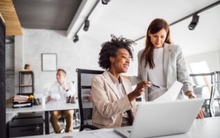 deux femmes discutent face ordinateur