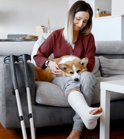 femme jambe dans le platre avec chien sur les genoux