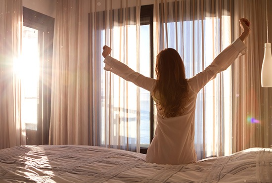 femme s'étirant au bord d'un lit