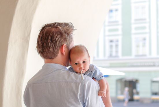 un bébé atteint du reflux gastro-oesophagien entrain de vomir sur le dos de son père