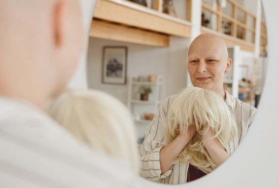 une femme ayant eu le cancer du sein qui est entrain porter sa perruque