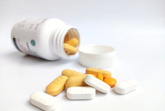 Flacon de comprimés ouverts contenant plusieurs pilules colorées représentant des anti-inflammatoires non stéroïdiens utilisés pour traiter la douleur et l’inflammation.