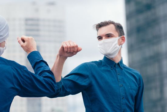2 hommes en train de se saluer en appliquant les gestes barrières