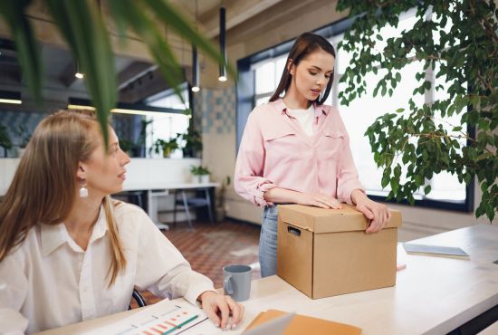 Femme reprenant le travail après un arrêt, échangeant avec une collègue dans un environnement professionnel apaisant.