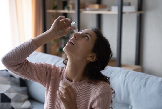 Femme utilisant un collyre sans conservateur pour soulager les symptômes du syndrome de l’œil sec chronique.