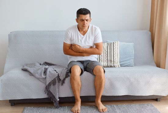 Homme souffrant de douleurs abdominales et de ballonnements, symptômes fréquents du syndrome de l'intestin perméable.
