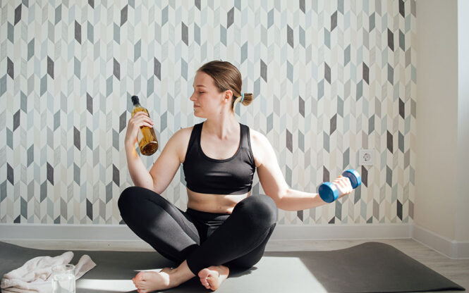 Femme faisant du sport et tenant une bouteille d'alcool