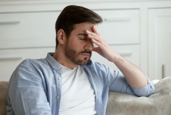 Un homme assis sur son canapé atteint de fatigue chronique