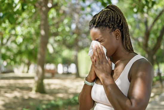 une femme allergique au pollen, entrain de se moucher