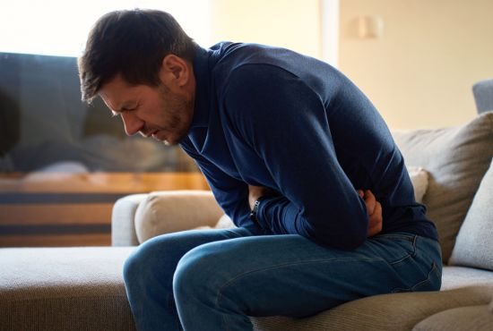 un homme recroquevillé sur lui même, ayant du mal à digérer