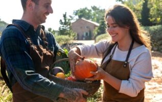 Un homme et une femme souriants tenant un panier rempli de légumes d'automne de saison, dont une courge.